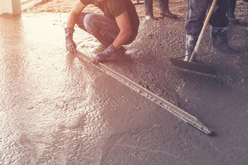 Man plasterer screed concrete on cement  for floor in building c - obrazy, fototapety, plakaty