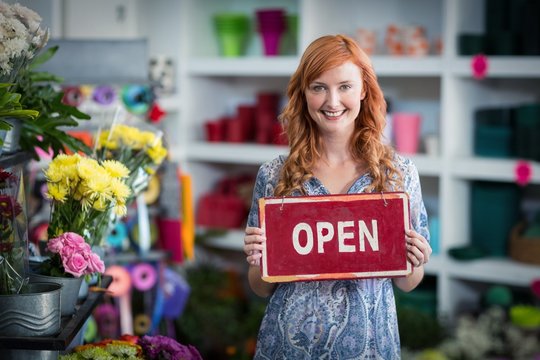 Smiling Florists Holding Open Sign Placard In Flower Shop