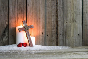 White candles, wooden cross and two red hearts