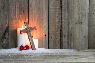 White candles, wood cross and red holiday ornaments