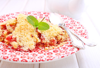 crumble with strawberries in white plate on a blue background