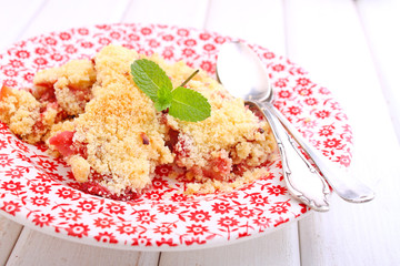 crumble with strawberries in white plate on a blue background