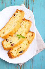 a piece of cake with raisins and candied fruit on a white plate on a blue background
