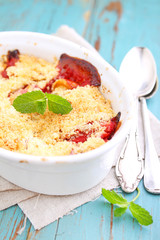 crumble with strawberries in white plate on a blue background