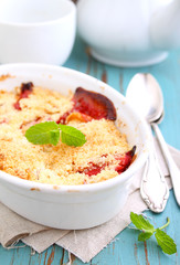 crumble with strawberries in white plate on a blue background