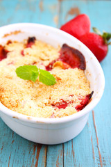 crumble with strawberries in white plate on a blue background