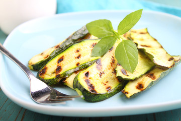 zucchini grilled on a blue plate with basil, selective focus.