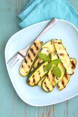 zucchini grilled on a blue plate with basil, selective focus.