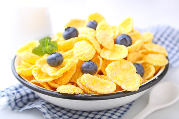 Cornflakes for breakfast with blueberries on a white background. Selective focus.