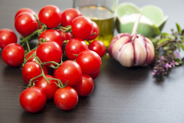 Cherry tomatoes branch with garlic, olive oil and basil. Selective focus.