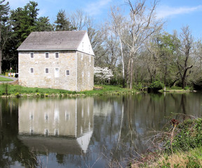 Fototapeta na wymiar Stone mill reflected in calm river in spring
