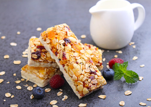 healthy snack, muesli bars with raisins and dried berries on a black background