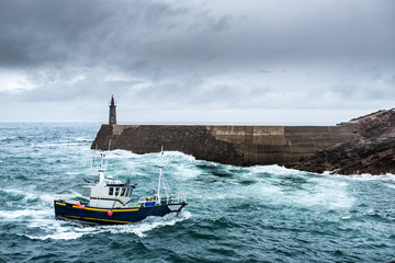 Fishing Vessel under Storm.arriving at pier. 
It's a boat or ship used to catch fish in the sea. Fishing can be affected by storms because of conditions like strong wind, precipitations or rain.

