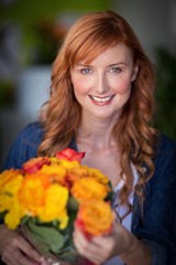 Fototapeta premium Portrait of female florist holding bunch of flowers