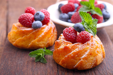 Sponge cakes with raspberries and blueberries on a wooden plank