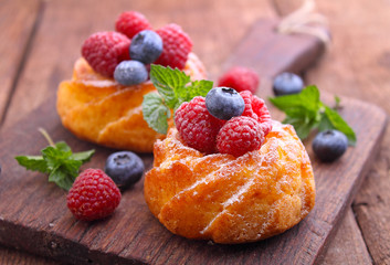 Sponge cakes with raspberries and blueberries on a wooden plank