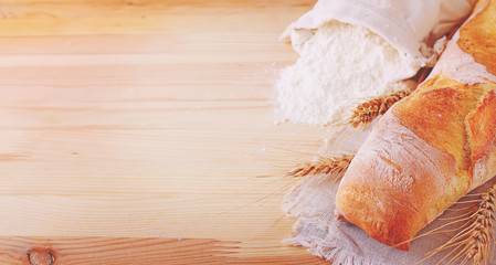 Baking ingredients: flour and ears on a light wooden background