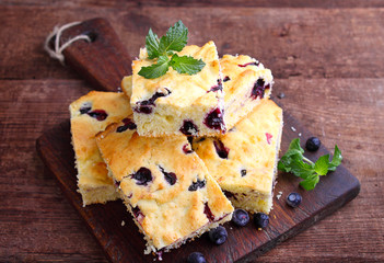 cake with blueberries cut into slices on old wooden board