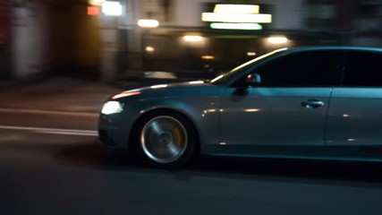 Side shot of a blue car driving in a city street at night