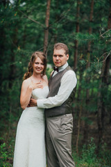 Naklejka premium Bride and groom are embracing against the background forest