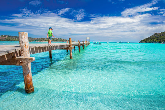 Little boy on the wooden bridge on Santa Giulia beach, Corsica, France