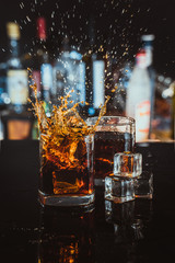 two glasses of whiskey on a blurred background bar - obrazy, fototapety, plakaty