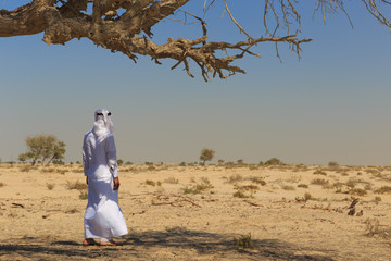 Arab man in national dress stands in the desert