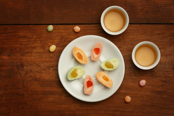 Colorful mochi rice cakes on white plate, porcelain cups with gr