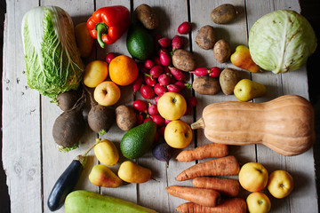 Fototapeta na wymiar Top view of the vegetarian set, consisting of vegetables and fruits lying on the wooden table closeup