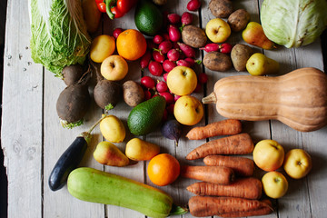 Fototapeta na wymiar Top view of the vegetarian set, consisting of vegetables and fruits lying on the wooden table closeup