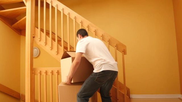 Young man feeling pain on his lower back due to heavy moving boxes.