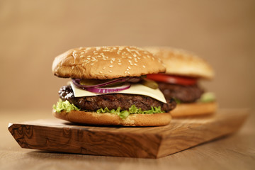 two homemade burgers on olive board on oak table