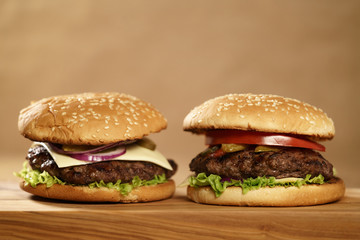 two homemade burgers on olive board on oak table