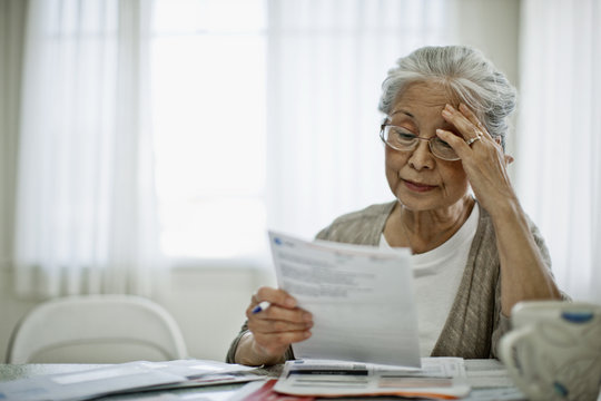 Anxious elderly woman is worried about how she can pay the bill she has received.
