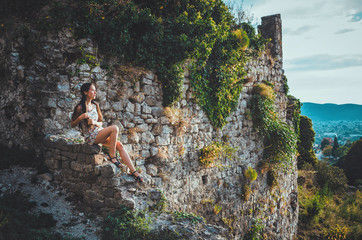 Attractive woman in Stari Bar old fortress, Montenegro. Brunette female with long hair in dress walks around castle, the magic atmosphere and fairy tales.