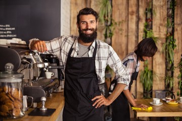 Smiling waiter standing in kitchen at café