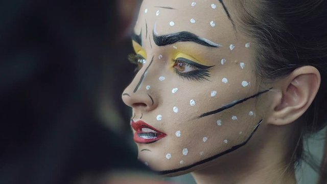 Artist drawing girl halloween makeup in studio