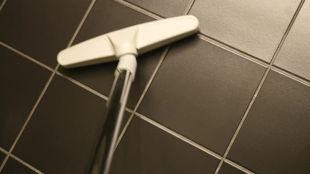 Closeup of a vacuum brush cleaning some tiles