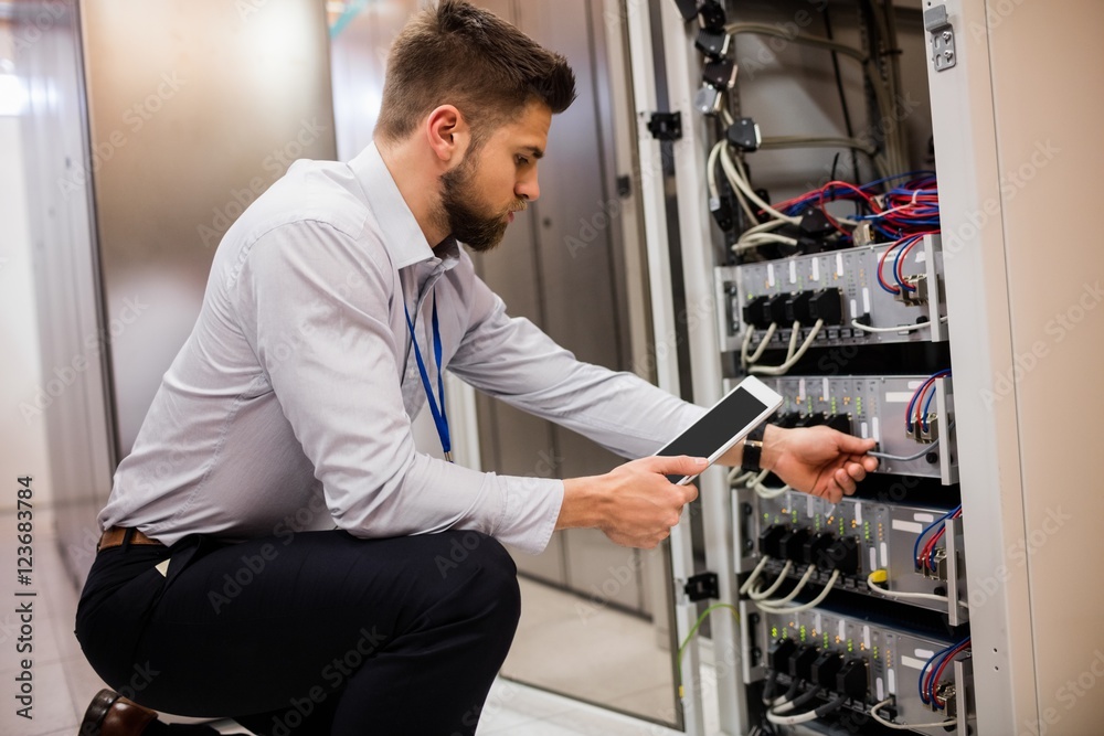 Fototapete Technician using digital tablet while analyzing server