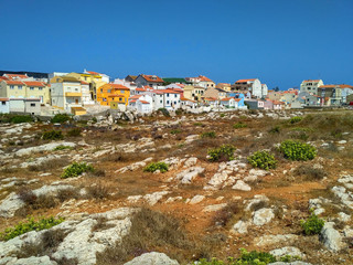 Obraz premium Colorful houses close to rocks on the ocean coast in Peniche