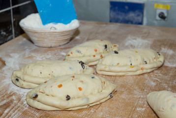 Christmas cake with raisins and candied fruit papaya, raw dough on a floured wooden table