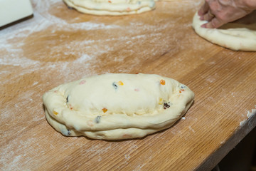 Christmas cake with raisins and candied fruit papaya, raw dough on a floured wooden table