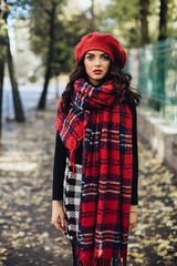 Beautiful happy girl in red hat and scarf walking in the autumn park