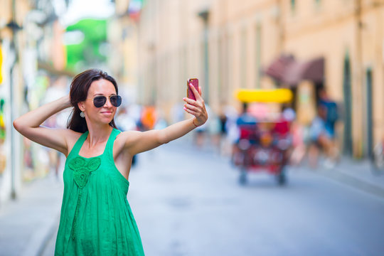 Woman take selfie by her smartphone in city. Young attractive tourist taking self photo outdoors in italian city