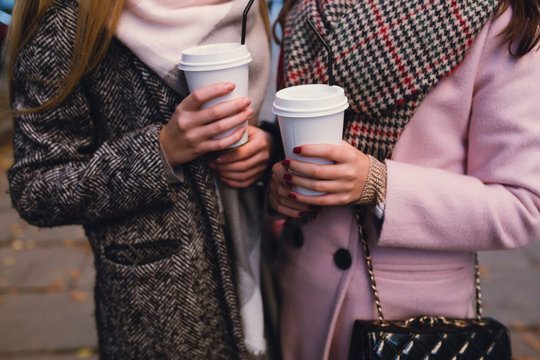 Two Stylish Girls Drinking Coffee And Talk In Autumn.