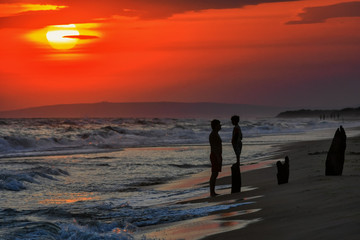 Father and son on a sea shore at sunset