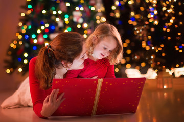 Mother and daughter reading at fire place on Christmas eve