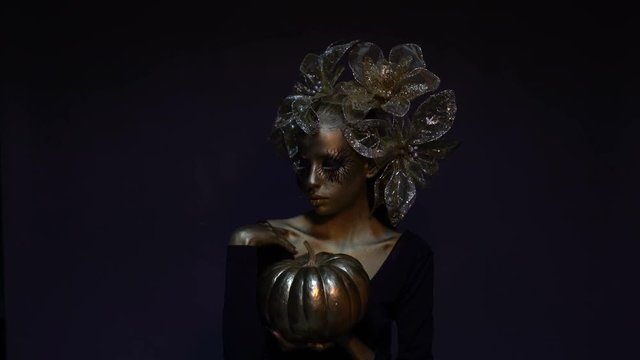 Halloween lady with golden pumpkin, creative way for the holidays, festive bodypainting