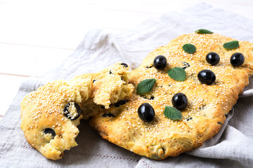 Italian bread focaccia with olive and herbs on linen napkin