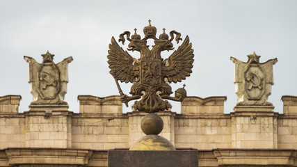Coat of arms of the Russian Federation. Coat of arms  on the background of the parapet of the administrative government building with Soviet symbols. Focus on the two-headed eagle.